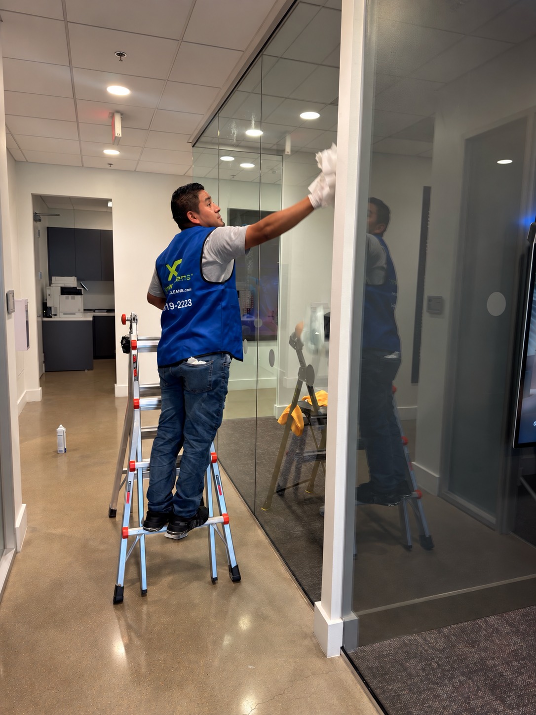 Xtreme Cleans team member cleaning glass inside a commercial office