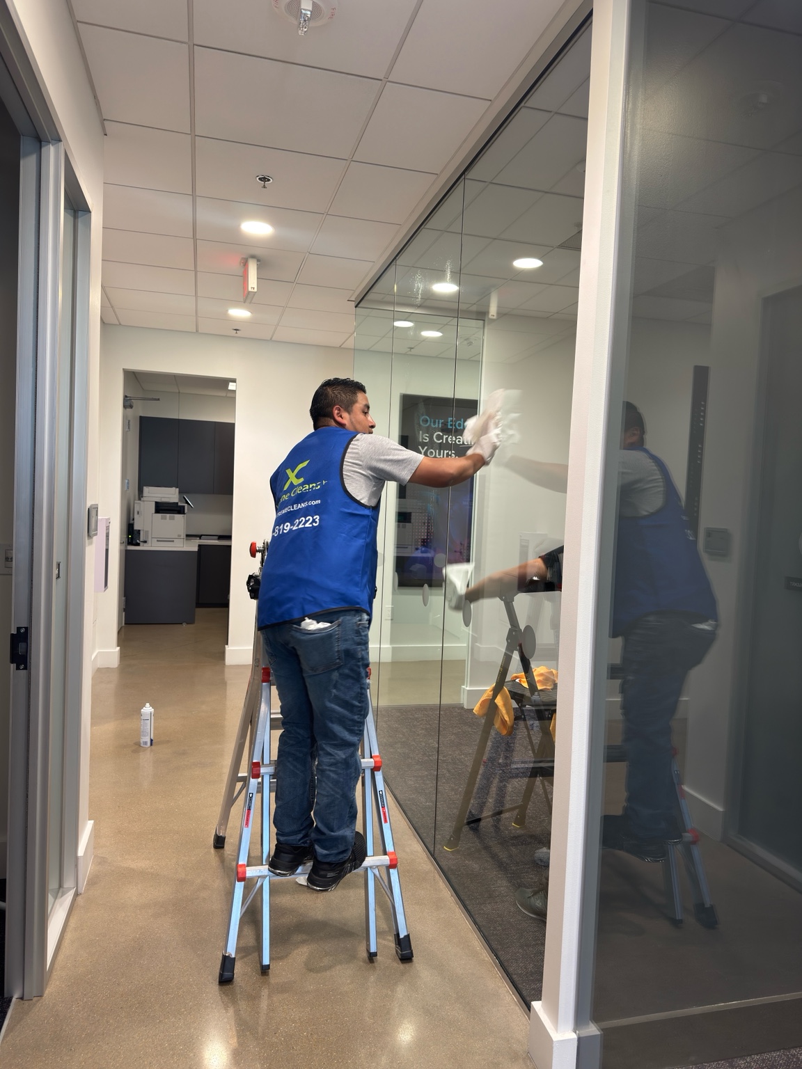 Xtreme Cleans employee wiping an office glass wall