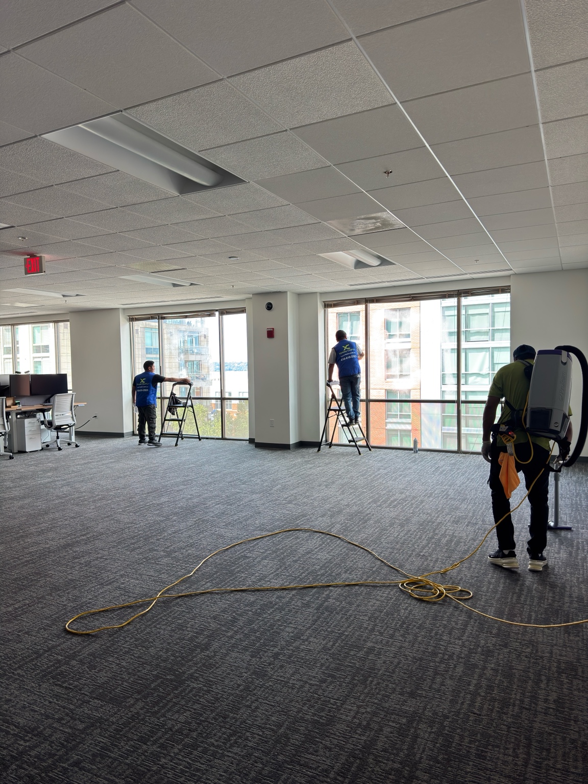 Xtreme Cleans team cleaning windows and vacuuming an office