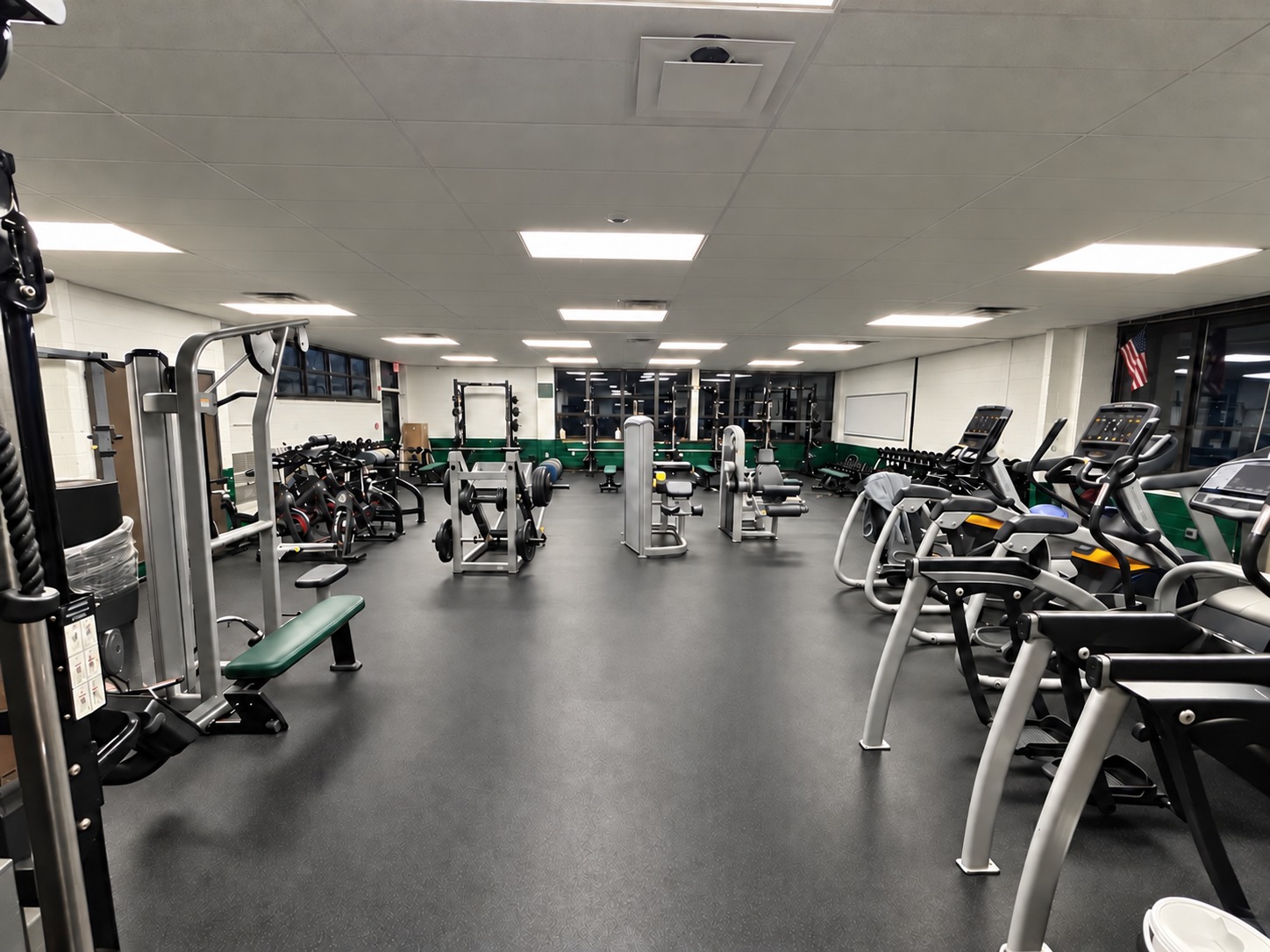Education-facility fitness room with exercise equipment and dark flooring