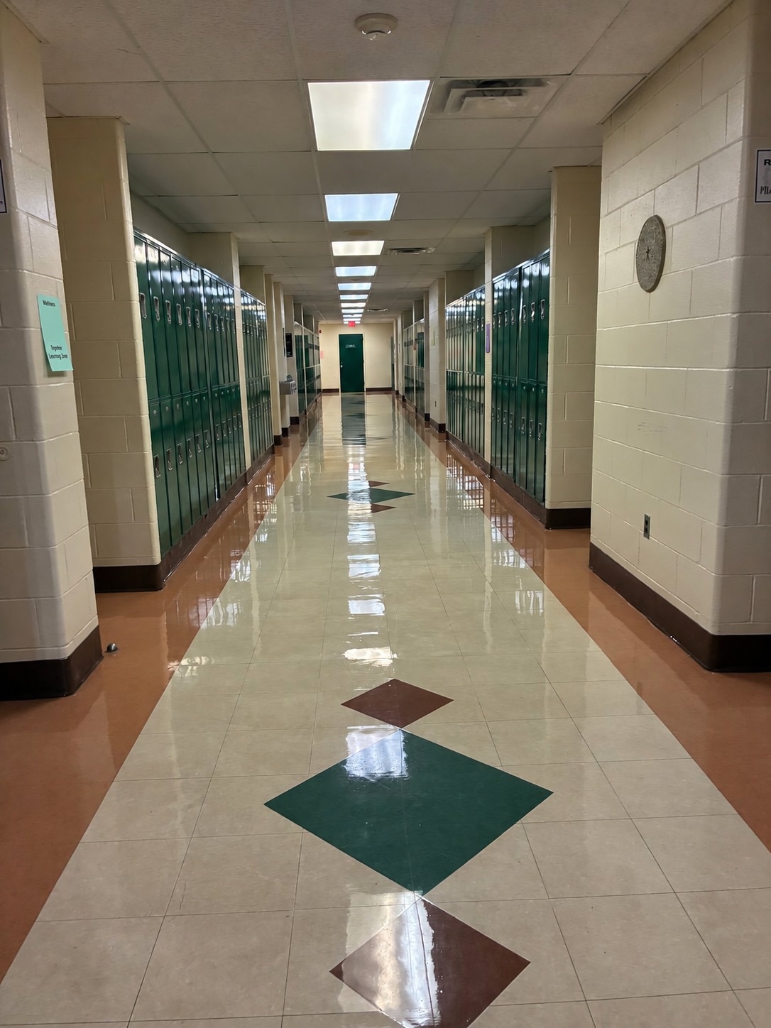 Straight view of a school corridor with green lockers and maintained hard flooring
